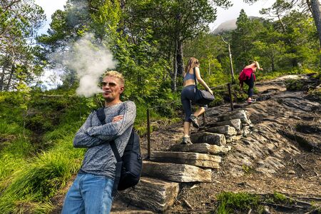 Man is standing and smoking while girl are going up