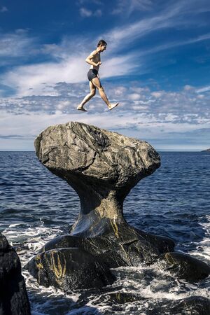 Young man is jumping on stone, Kannesteinen, Norwayの写真素材