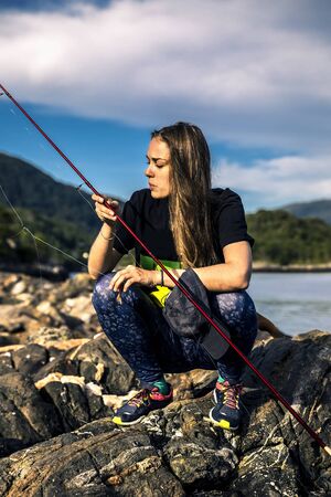 Young woman is fishing in Norway in the fjord.の写真素材
