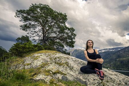 Young woman is exercising on the fjord, Norwayの写真素材