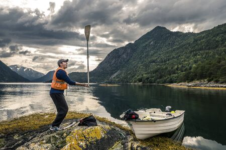 Young man is having fun with paddle near by boat, Norwayの写真素材