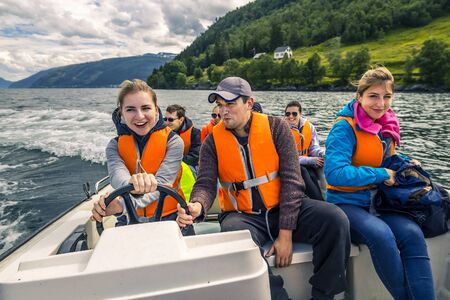 Portrait of young and attractive people, friends in the motorboat driving somewhere on a picnic. Happy faces, having fun, Norway.の写真素材