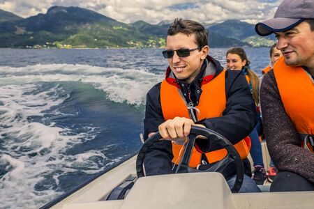 Portrait of young and cheerful man close up driving the motorboat, Norway. He is enjoying the moment.の写真素材