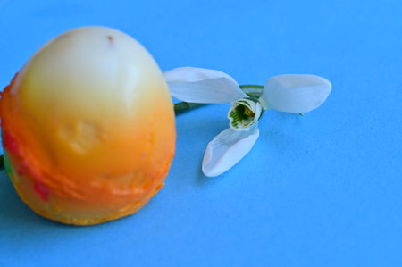 Easter egg with snowdrops and candle on blue background, selective focusの写真素材