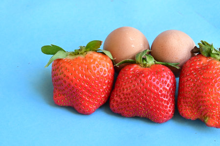 Strawberries and eggs on a blue background. Healthy food.の写真素材