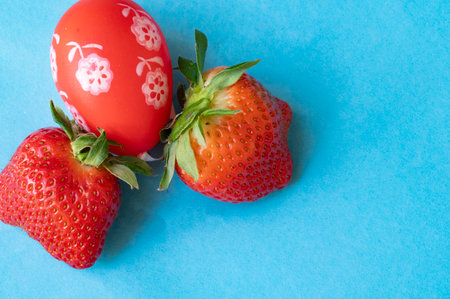 Strawberries and Easter egg on blue background. Copy space.の写真素材