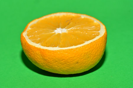 A slice of orange on a green background. Close-up.