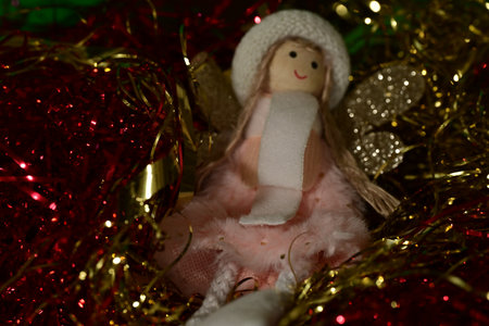Christmas decoration with angel doll and tinsel on a red background.の写真素材