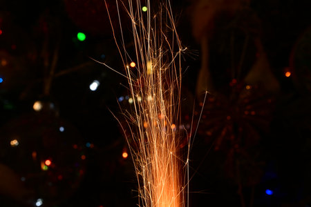 sparkler on a christmas tree with lights in the background