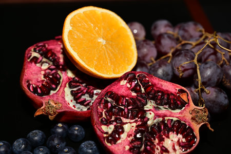 Pomegranate, blueberries and orange on a black backgroundの写真素材