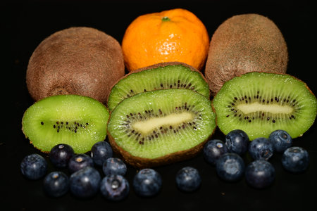 Kiwi, tangerine and blueberry on black backgroundの写真素材