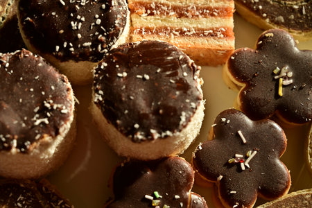 Delicious mini cakes with chocolate icing and sprinkles, closeup