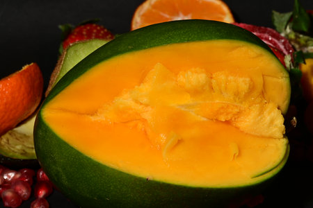 Close up of a melon with fruits on a black background.