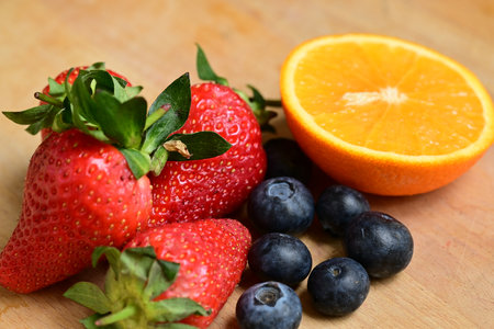 Fresh fruits on a wooden background. Strawberries, blueberries and orangesの写真素材