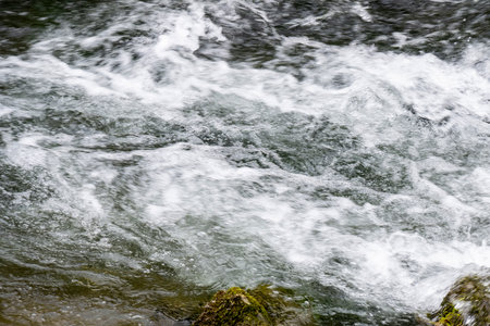 Detail of a waterfall in the forest with rocks and moss.
