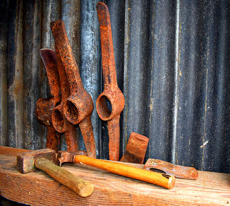 Rusty pick axe heads and a hammer in a tool shedの写真素材