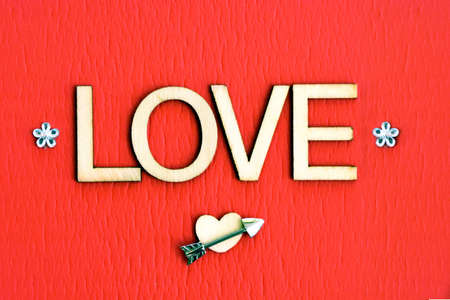 Wooden letter spelling â€˜LOVEâ€™ with an arrow, heart and small bouquet.