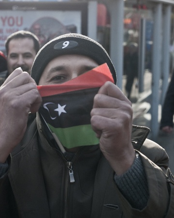 HYDE PARK, LONDON, ENGLAND - March 10, 2011: A demonstrator proudly holds Libyan flag as anti-Gaddafi, pro-democracy protesters rally outside the Libyan Embassy on the corner of Hyde Park, London on March 10, 2011.のeditorial素材