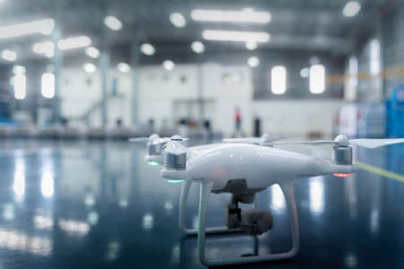 low angle shot of a Drone camera about to take off to survey over a smart factory , industrial facility enabling IOT, tracking goods and inventory, logistic mapping in a futuristic world.の写真素材