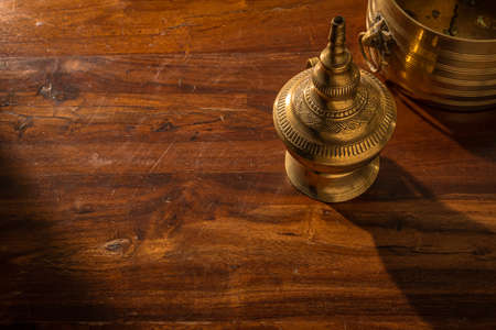 Close up of traditional brass lamp artifacts from southern India on a wooden table