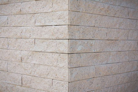 Background of the cream brick wall corner. The bricks are made from natural rock and pebbles.の写真素材