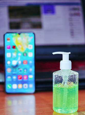 Green gel alcohol With a mixture of aloe vera in a pump-like bottle placed on the work desk, Together with the background of the smart phone and laptop.の写真素材