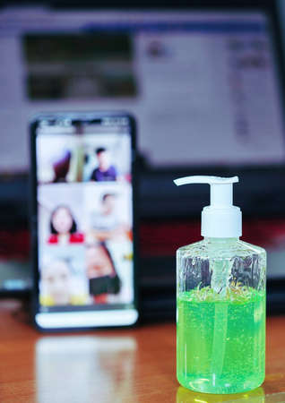 Green gel alcohol With a mixture of aloe vera placed on the work desk, Together with the background of the smart phone and laptop. Video calling on a mobile phone to be social distancing.の写真素材