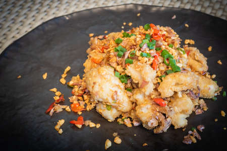 Deep fried sea bass with chili and salt in a black plate, served on the dining table. Snapper is a diet that helps you lose weight and improve your brain.の写真素材