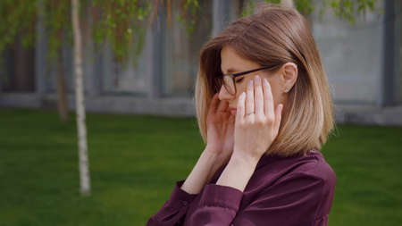 Close up Portrait  sad young woman suffering bad headache touching her temples outdoor. Migraine. Unhappy face. Presuure. Emotional suffer face.の写真素材
