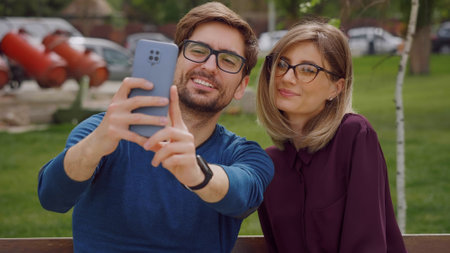 Head shot Caucasian woman and man close up portrait ,wearing glasses take selfie with smartphone smiling positive mood. Social networking outdoors. Friendship portrait concept.の写真素材