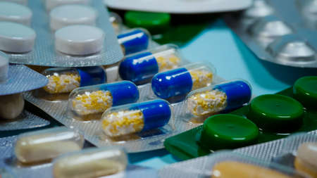 Blister pack, Pills, tablets and capsules of various shapes and colors on blue background