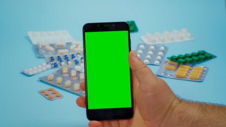 Man Use phone with Chroma Key Display for Medication Information. Prospectus pills. Using Smarthphone with Mockup, Green Screen Medical. Various Pills blisters.の写真素材