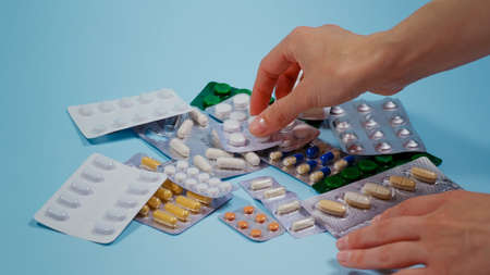 Pile of pills in blister packs on blue background. Taking blister pill.の写真素材