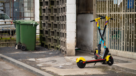 BUCHAREST, ROMANIA - May 15, 2021: Two electric scooters on the sidewalk behind a block next to a trash canのeditorial素材
