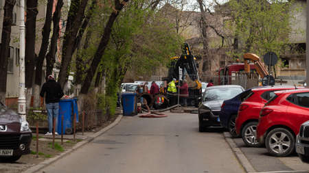 Workers carry out repair work on the city sewer. Tractor, repair in the city, hole in the asphalt.のeditorial素材
