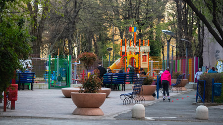 BUCHAREST, ROMANIA - May 15, 2021: Modern playground with soft surface and a large children's slide. Active family holiday in the park. Children skates on asphalt and goes round cones.のeditorial素材