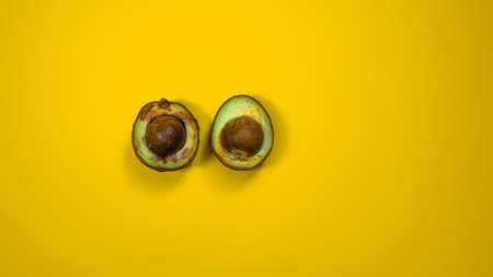 Two Half Bad Avocado.The seed avocado and the inside is visible. Rotten Avocado on yellow background Copy space.の写真素材