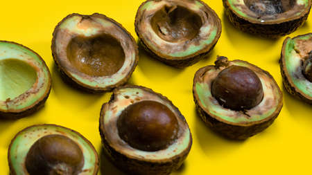 Halfs rotten avocados on yellow table. Unhelthy food Concept. Close up bad avocado on yellow...