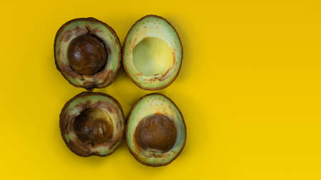 Ugly food on yellow background. Bad avocado. Rotten tropical fruits. Concept of rotten fruit. Copy space on yellow background.の写真素材