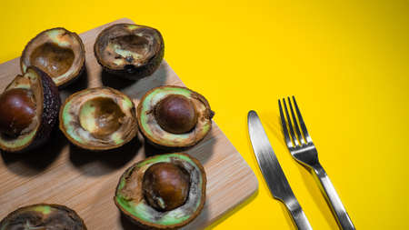 Halfs rotten avocado. Unhelthy food Concept. Close up bad avocado on yellow background. Ugly fruits.