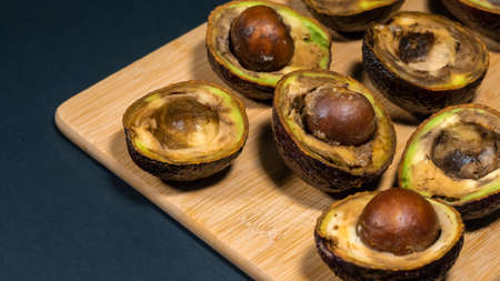 Rotten Avocados Halfs on table. Bad Fruits on wood Chipper. Overripe avocado close up.の写真素材