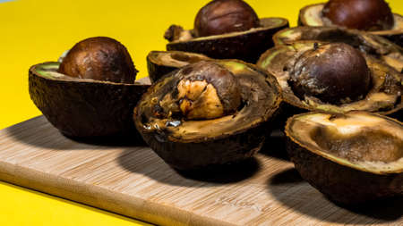 Bad Avocado Halfs on Yellow background. Bad Vegan food. Rotten Avocado on wood Chipper next fork and knife. Necomestibile Food. Stop wasting food. Overripe Fruits Concept cannot be eaten. Copy space.の写真素材