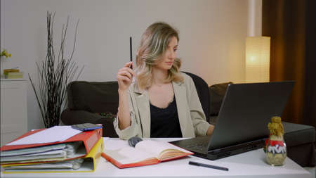 Young business woman working on project paperwork. Female manager making business notes on notebook, working alone in office.の写真素材