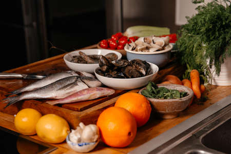 Sea bream and shells on the table next to vegetables and fruit. Ingredients for making a delicious soup.の写真素材