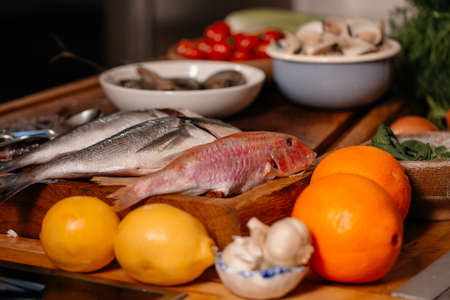 Sea bream and shells on the table next to vegetables and fruit. Ingredients for making a delicious soup. Fine cuisine.の写真素材