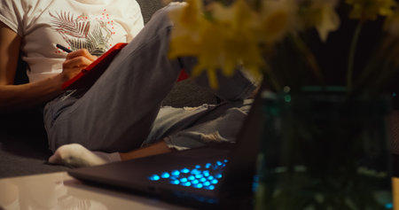 Young woman writing notes with laptop home.の写真素材