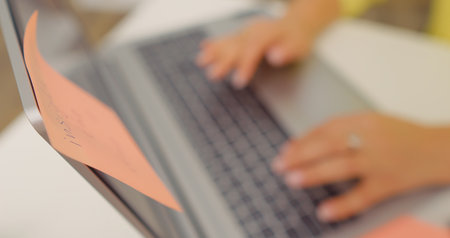 Selective focus of unrecognized woman typing a document on laptop. Office worker preparing papers...