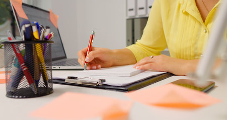Woman hand taking notes of her new ideas working remotely. Business woman working online from home.の写真素材