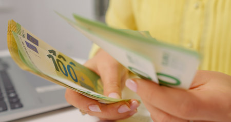 Woman count money euro at desk in home office. Receiving payment female counting her money.の写真素材