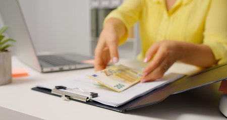 Woman opening the clipboard and raising a pile of money. Accountant taking money out of a clipboard.の写真素材